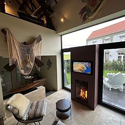 Cozy indoor area of Holiday Home Einzigartiger Wellness-Bauernhof in Wichelen, East Flanders with fireplace and garden view.