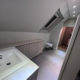 Moderne badkamer in appartement /, Bevere, Oost-Vlaanderen, Belgie, met strakke lijnen en dakraam voor natuurlijk licht.