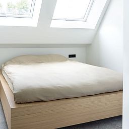 Schlafzimmer im Ferienhaus in Sint-Pieters-Leeuw, Flaemisch-Brabant, Belgien, mit bequemem Bett und Oberlichtern fuer natuerliches Licht.