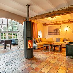 Gezellige woonkamer in vakantiehuis Alverwege, Merksplas, Antwerpen, met een warme haard en ruime zithoek voor ontspanning in een landelijke sfeer.