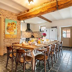 Gezellige eetruimte in vakantiehuis Alverwege, Merksplas, Antwerpen met rustieke houten balken en een ruime eettafel voor groepsdiners.