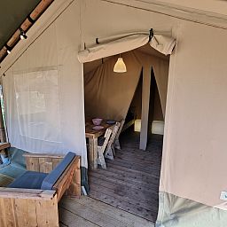 Entdecken Sie das gemuetliche Innere des Safari-Zeltes, einer Glamping-Lodge in Brecht, Antwerpen, ideal fuer einen rustikalen Urlaub.