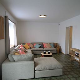 Gemuetliches Wohnzimmer im Huisje Nostalgie, Laakdal, Antwerpen, mit bequemen Sofas und bunten Kissen.