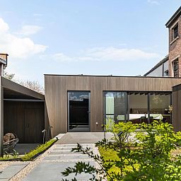Pastorie Liezele vakantiehuis in Puurs-Sint-Amands, Antwerpen, met moderne architectuur en groene tuin voor een ontspannen verblijf.