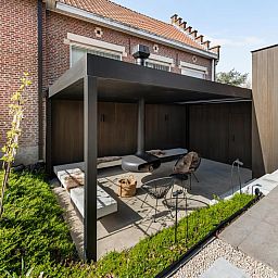 Gezellige veranda bij Pastorie Liezele, vakantiehuis in Puurs-Sint-Amands, Antwerpen, met moderne zitruimte en groene omgeving.