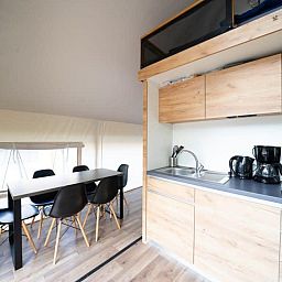 Modern kitchen and dining area in Kiezel Lodge XL, a luxury glamping lodge in Mol, Antwerp, Belgium, with wooden finishes and comfortable seating.