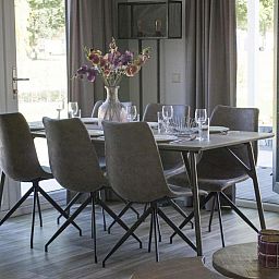 Dining area in vacation home Velthorst, Mol, Antwerp with modern decor and views of nature through large windows.