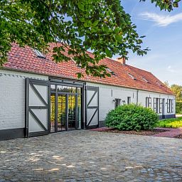 Fassade von Mushoeve in Zoersel, Antwerpen, Ferienhaus mit charmanter weisser Fassade und roten Dachziegeln.