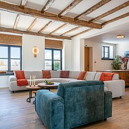 Cozy living room in Lindehoeve vacation home, Turnhout, with comfortable seating and wooden beams.