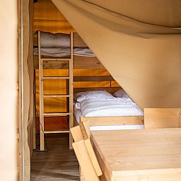Gemuetliches Schlafzimmer in Safaritent, einer Glamping-Lodge in Turnhout, Antwerpen, Belgien, mit Etagenbetten und Holzinterieur.