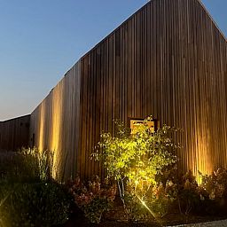 Atmospherically lit exterior of Holiday Home in Kasterlee, Antwerp, Belgium, surrounded by green nature at dusk.