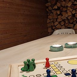 Gemuetlicher Innenbereich des Ferienhauses in Herselt, Antwerpen, Belgien, mit Holzwaenden und einem Brettspiel auf dem Tisch.