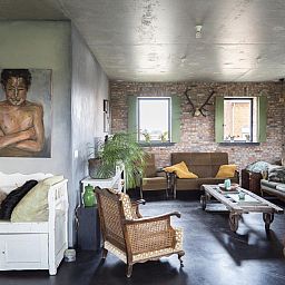 Gezellige woonkamer van vakantiehuis De Lieshoeve in Arendonk, Antwerpen, met vintage meubels en kunst aan de muur.