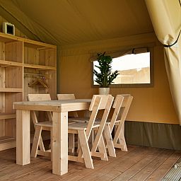 Cozy interior of Safari tent incl. sanitary facilities in Lichtaart, Antwerp. Glamping lodge with wooden furniture and natural atmosphere.