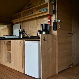 Cozy kitchen in Safari tent incl. plumbing, a glamping lodge in Lichtaart, Antwerp, Belgium, with wooden interior and modern amenities.