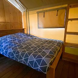 Cozy bedroom in Safari tent incl. sanitary facilities, located in Lichtaart, Antwerp, Belgium. Experience luxury glamping in a comfortable tent.