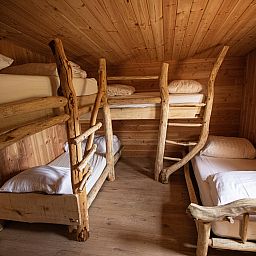 Gezellige slaapkamer in Hobbit House 1, uniek vakantiehuis in Neeroeteren, Limburg, Belgie, met rustieke houten stapelbedden.