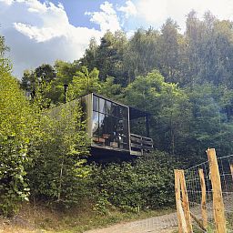 Watercabin met hottub in Neeroeteren, Limburg, Belgie, omgeven door weelderige natuur, ideaal voor een rustgevend verblijf in een vakantiehuis.
