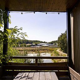 Geniet van het uitzicht vanaf de veranda van de Watercabin met hottub in Neeroeteren, Limburg, Belgie, omgeven door prachtige natuur.