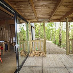 Binnenruimte van Comfort Classic vakantiehuis in Neeroeteren, Limburg, Belgie, met uitzicht op veranda en omliggende bossen.