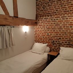 Gezellige slaapkamer in Servaeshoeve - Gerstebaard, vakantiehuis in Borgloon, Limburg, Belgie met rustieke bakstenen muur en houten balken.