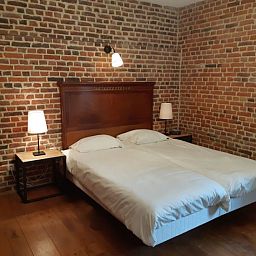 Gezellige slaapkamer in Servaeshoeve - Gerstebaard, een vakantiehuis in Borgloon, Limburg met rustieke bakstenen muren en sfeervolle verlichting.