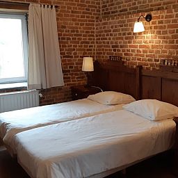 Gezellige slaapkamer in Servaeshoeve - Gerstebaard, vakantiehuis in Borgloon, Limburg, Belgie, met rustieke bakstenen muren en houten meubels.