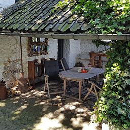 Gezellige veranda bij Huisje in Sint Pietersvoeren, een vakantiehuis in Limburg, Belgie, omringd door groene natuur en rustieke charme.