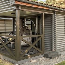 Veranda van Mooi Zutendaal 4-6-persoons chalet in Limburg, Belgie, met comfortabele zitplek en uitzicht op groene omgeving.