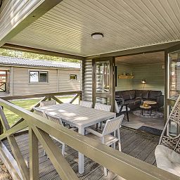 Veranda van Mooi Zutendaal chalet in Limburg, Belgie, met buitenzitje en uitzicht op groene omgeving.