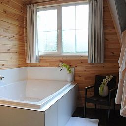 Ontspan in de luxe badkamer van Mooi Zutendaal 4-persoons bungalow in Zutendaal, Limburg, Belgie, met een ruim bad en houten interieur.