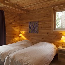 Gezellige slaapkamer in Mooi Zutendaal 4-persoons bungalow, Limburg. Houten interieur met comfortabele bedden en sfeervolle verlichting.