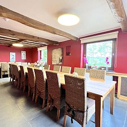 Grosses Esszimmer im Ferienhaus Aux Hirondelles in Malmedy, Ardennen, mit Holztischen und Stuehlen.