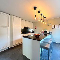 Moderne Kueche des Ferienhauses Aux Hirondelles in Malmedy, Ardennen, mit Bar und Beleuchtung.