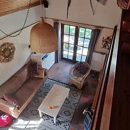 Gemuetliches Wohnzimmer des Chalets Pont du Waud in Waimes, Ardennen, Belgien, mit bequemer Sitzecke und Blick auf den Garten.