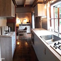 Gemuetliche Kueche im Chalet Pont du Waud, einem Ferienhaus in Waimes in den Ardennen, Belgien, mit Blick auf die gruene Natur durch grosse Fenster.