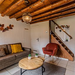 Gezellige binnenruimte van Village les Gottales 4-persoons bungalow in Trois-Ponts, Ardennen. Houten balken en comfortabele zithoek.