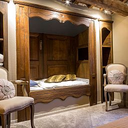 Cozy bedroom in Holiday Home Villa 'Marie France' Wellness, Stavelot, Ardennes, with authentic wooden bed and elegant chairs.