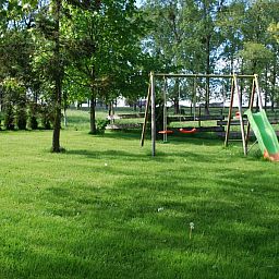 Speelplaats met schommel bij Gites d'Ogne vakantiehuis in Sprimont-Ogne, Ardennen, omgeven door natuur en bomen.