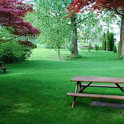 Picknicktafels in de tuin van Gites d'Ogne vakantiehuis in Sprimont-Ogne, Ardennen, ideaal voor buitenmaaltijden.