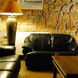Gezellige zithoek met leren banken in Gites d'Ogne vakantiehuis in Sprimont-Ogne, Ardennen, met sfeervolle stenen muur.