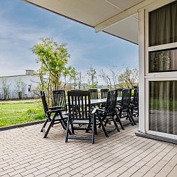 Ruim terras van Village l'Eau d'Heure 12-persoons bungalow in Froidchapelle, Henegouwen, Belgie, met comfortabel tuinmeubilair en uitzicht op groen.