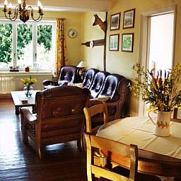 Sfeervolle woonkamer van Les Gronsarts Vencimont vakantiehuis met houten meubels en grote ramen in de Ardennen, Belgi.