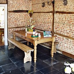 Rustieke eetkamer in Les Gronsarts Vencimont vakantiehuis met houten tafel en bakstenen muur in Vencimont, Ardennen.