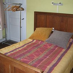 Attractive bedroom in L'Odasse, vacation home Bohan, Ardennes, with wooden bed and colorful blankets.