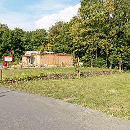 Luxe kampeerplaats C1 in Gesves, Ardennen, Belgie, biedt een rustieke stacaravan te midden van weelderige natuur en groene omgeving.