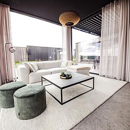 Modernes Wohnzimmer im Ferienhaus La Ruree, Heure, Ardennen, Belgien, mit stilvoller Einrichtung und grossen Fenstern fuer natuerliches Licht.