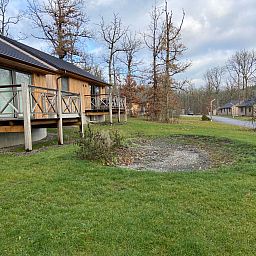 Ferienhaus Modernes Chalet fuer 4 Personen in Heure, Ardennen, Belgien, mit Holzveranda und Blick auf die waldreiche Umgebung.