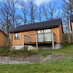 Ferienhaus Modernes Chalet fuer 4 Personen in Heure, Ardennen, Belgien, umgeben von waldreicher Natur mit einer einladenden Veranda.
