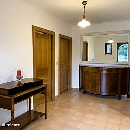 Der elegante Eingangsbereich der Villa La Meuse - De Maas, einem Ferienhaus in Dinant in den Ardennen, Belgien, mit Holzmoebeln und warmer Beleuchtung.